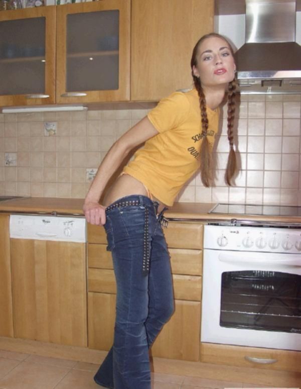 Женщина в джинсах раздевается на кухне