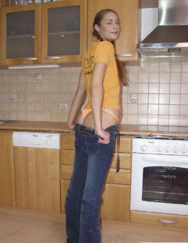 Женщина в джинсах раздевается на кухне